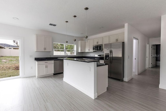 kitchen with stainless steel appliances, pendant lighting, white cabinetry, and a center island