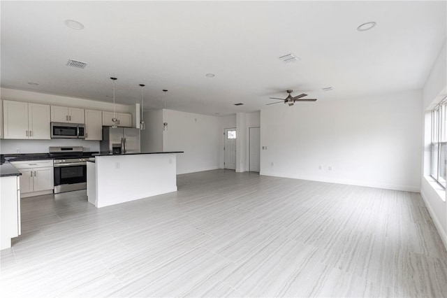 kitchen featuring ceiling fan, stainless steel appliances, pendant lighting, white cabinets, and a center island