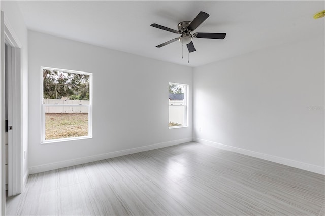 empty room with ceiling fan and a wealth of natural light