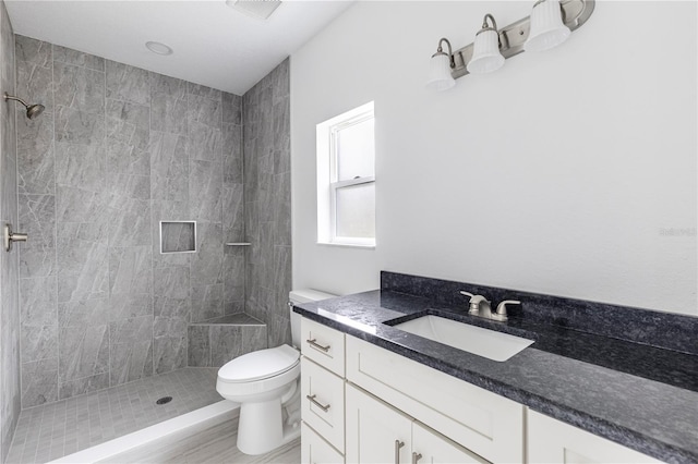 bathroom featuring toilet, vanity, and a tile shower