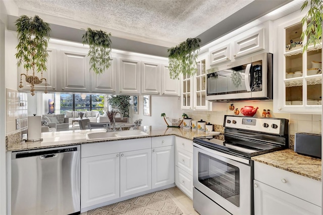 kitchen featuring light stone countertops, white cabinetry, sink, stainless steel appliances, and light tile patterned floors