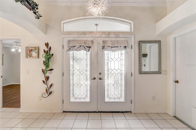 tiled entryway featuring french doors and ceiling fan with notable chandelier