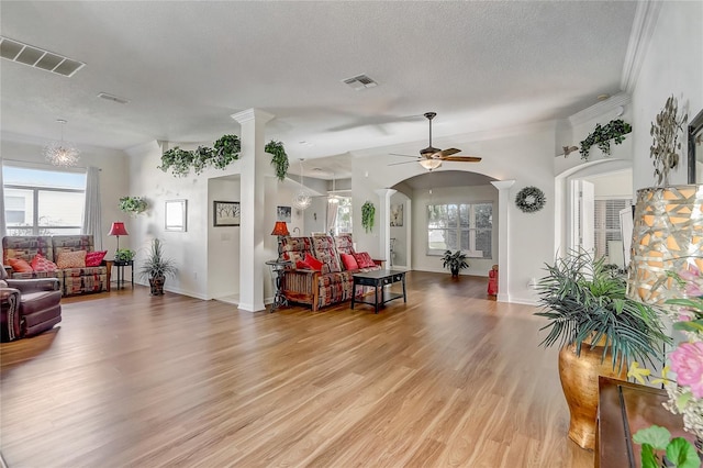 living room with ornate columns, ornamental molding, a textured ceiling, ceiling fan, and light hardwood / wood-style flooring