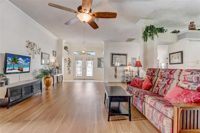 living room featuring french doors, light wood-type flooring, ornamental molding, a textured ceiling, and ceiling fan