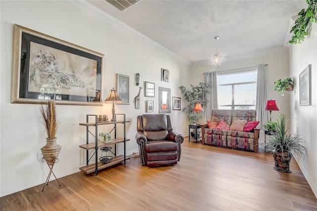 sitting room featuring a notable chandelier, crown molding, wood-type flooring, and a textured ceiling