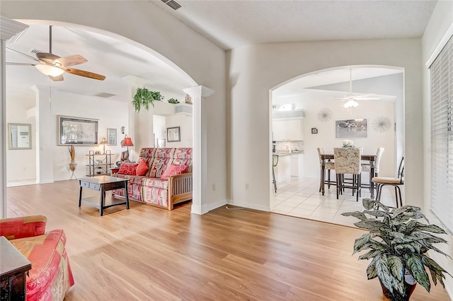 living room with ceiling fan, light hardwood / wood-style floors, and lofted ceiling