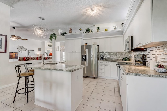 kitchen with stainless steel appliances, white cabinets, backsplash, a textured ceiling, and light tile patterned flooring