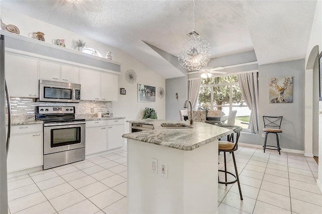 kitchen featuring sink, hanging light fixtures, stainless steel appliances, decorative backsplash, and white cabinets