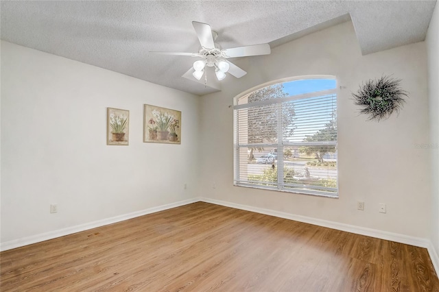 spare room with lofted ceiling, ceiling fan, light hardwood / wood-style floors, and a textured ceiling