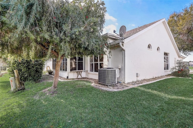 back of property featuring central AC unit, a sunroom, and a yard