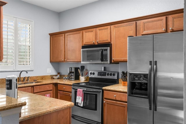 kitchen with a wealth of natural light, light stone counters, sink, and stainless steel appliances