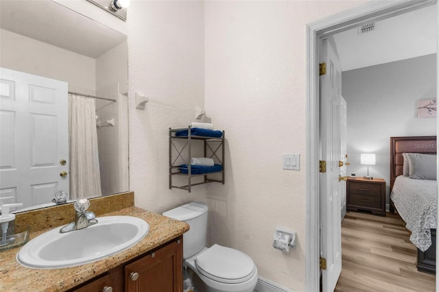 bathroom featuring hardwood / wood-style floors, vanity, toilet, and curtained shower