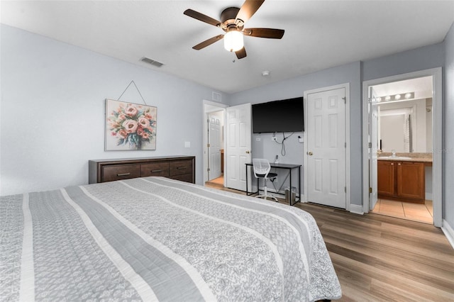 bedroom featuring wood-type flooring, ensuite bathroom, ceiling fan, and sink