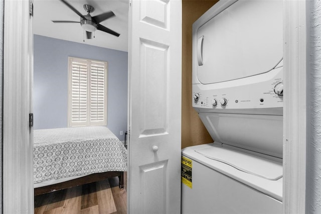 laundry room with hardwood / wood-style floors, stacked washing maching and dryer, and ceiling fan