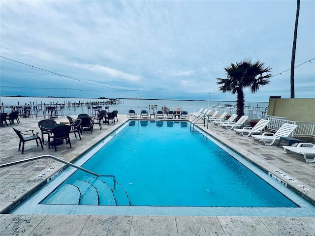 view of swimming pool featuring a water view and a patio area