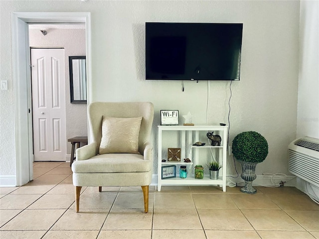 living area featuring a wall mounted AC and tile patterned flooring