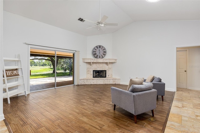 living room with hardwood / wood-style flooring, ceiling fan, lofted ceiling, and a high end fireplace