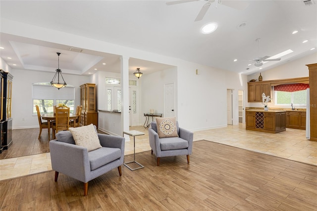 living room featuring a tray ceiling, ceiling fan, a healthy amount of sunlight, and sink