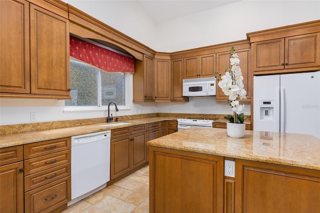 kitchen featuring light stone countertops, sink, and white appliances