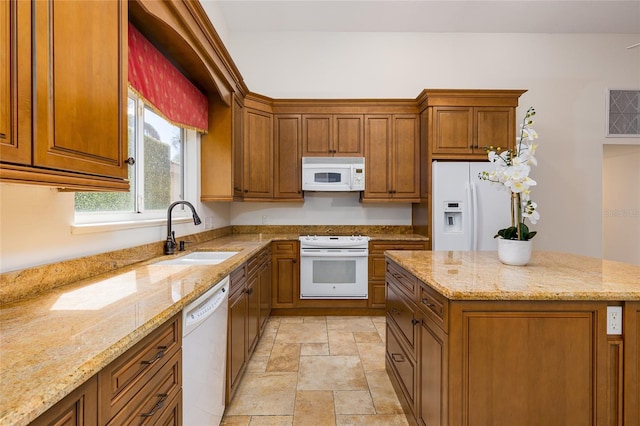 kitchen with white appliances, light stone counters, and sink