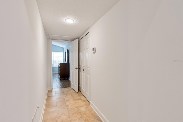 corridor with a textured ceiling and vaulted ceiling