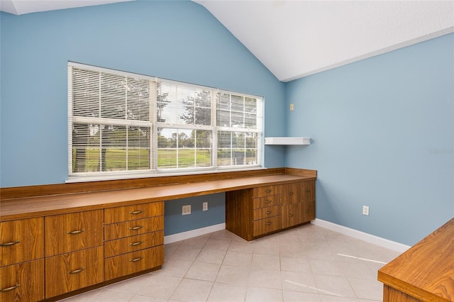 unfurnished office featuring light tile patterned floors, built in desk, and lofted ceiling