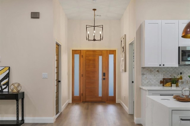 entrance foyer with a chandelier, a high ceiling, and light wood-type flooring