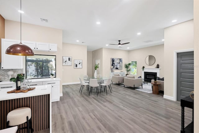 kitchen with white cabinets, ceiling fan, pendant lighting, and light wood-type flooring