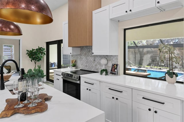 kitchen featuring decorative backsplash, white cabinetry, and electric stove