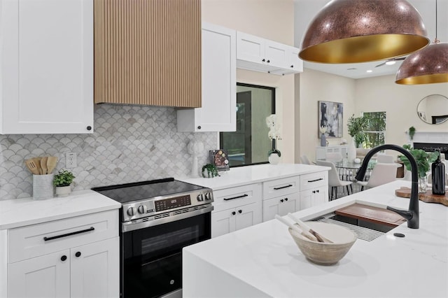 kitchen featuring stainless steel electric range oven, sink, light stone countertops, tasteful backsplash, and white cabinets