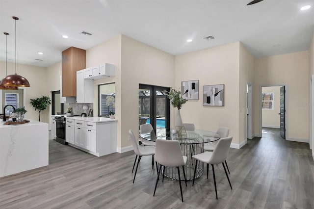 dining space featuring hardwood / wood-style floors, a towering ceiling, french doors, and sink