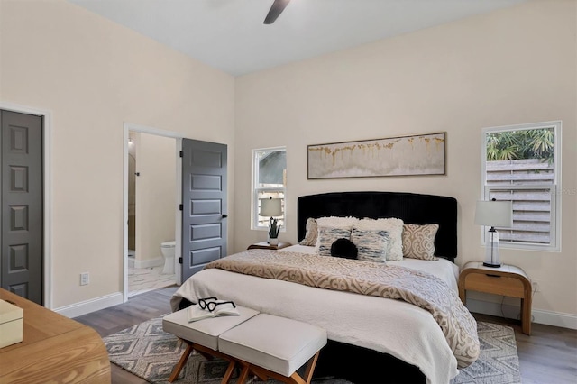 bedroom with connected bathroom, ceiling fan, a towering ceiling, and hardwood / wood-style flooring