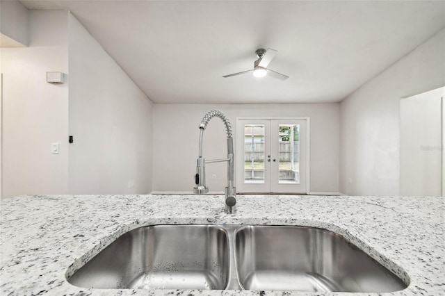 details with ceiling fan, light stone counters, sink, and french doors