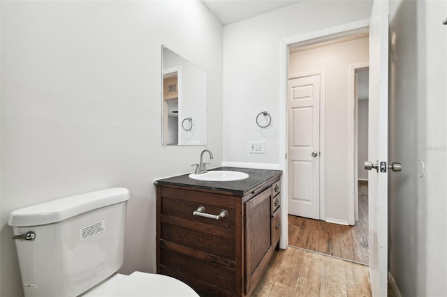 bathroom with hardwood / wood-style floors, vanity, and toilet