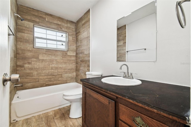 full bathroom with hardwood / wood-style floors, vanity, tiled shower / bath combo, and toilet