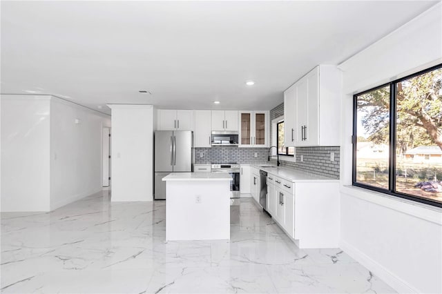 kitchen with stainless steel appliances, a center island, sink, and white cabinets