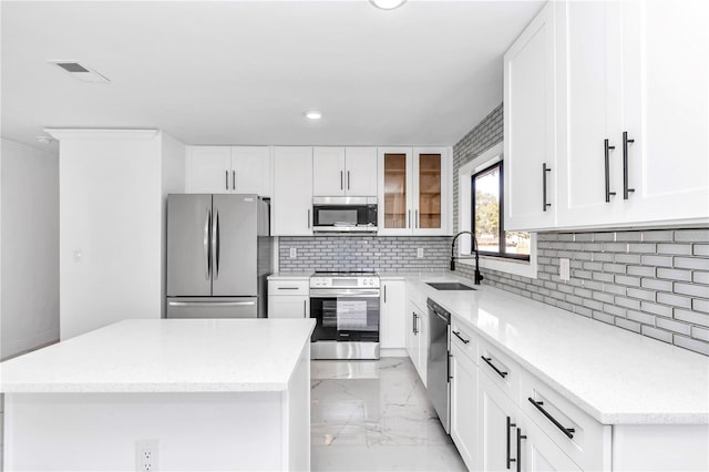 kitchen featuring sink, a center island, stainless steel appliances, decorative backsplash, and white cabinets