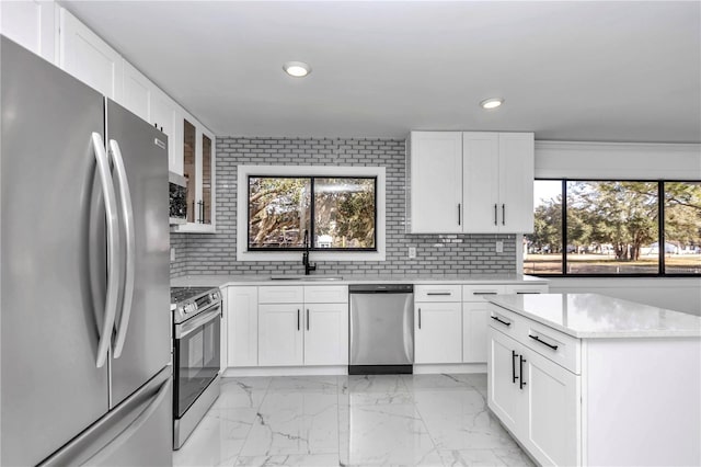 kitchen with white cabinetry, stainless steel appliances, sink, and tasteful backsplash