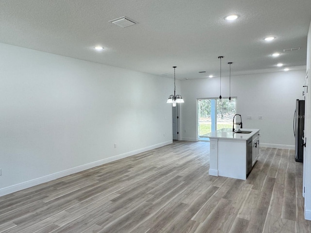 kitchen featuring pendant lighting, sink, an island with sink, a textured ceiling, and stainless steel appliances