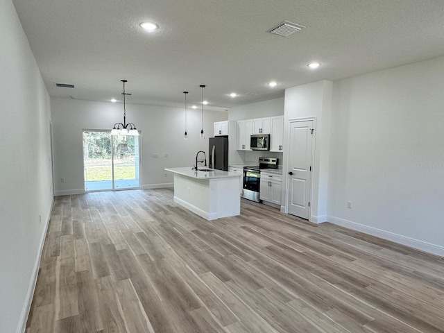 kitchen featuring a kitchen island with sink, white cabinets, hanging light fixtures, sink, and stainless steel appliances