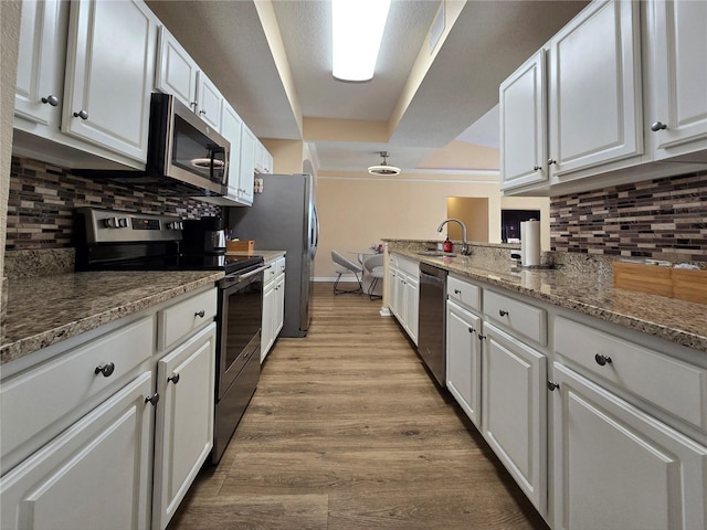 kitchen featuring decorative backsplash, appliances with stainless steel finishes, light stone counters, light hardwood / wood-style floors, and white cabinetry