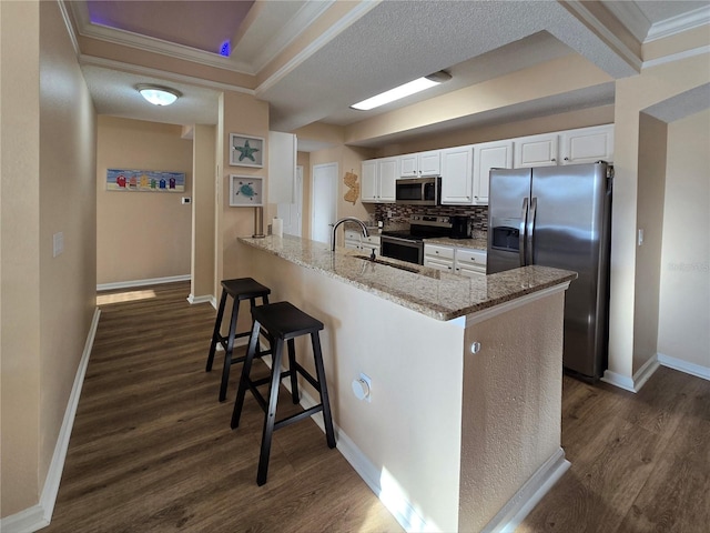 kitchen featuring a breakfast bar, white cabinets, light stone countertops, kitchen peninsula, and stainless steel appliances