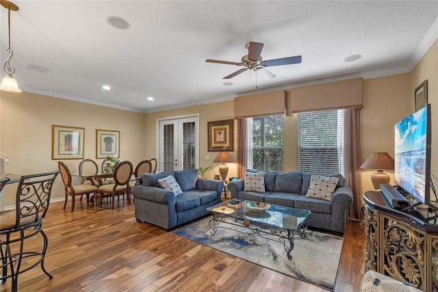 living room with ceiling fan, french doors, dark hardwood / wood-style floors, a textured ceiling, and ornamental molding