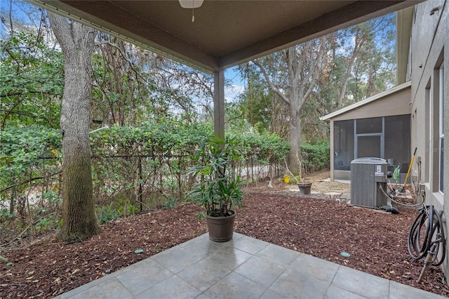 view of patio featuring central air condition unit, ceiling fan, and a sunroom