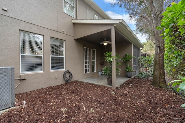 view of exterior entry with a patio area, ceiling fan, and central AC