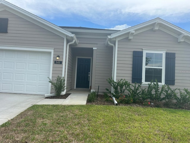 doorway to property with a garage and a yard