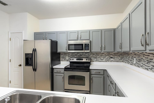 kitchen with backsplash, appliances with stainless steel finishes, and gray cabinets