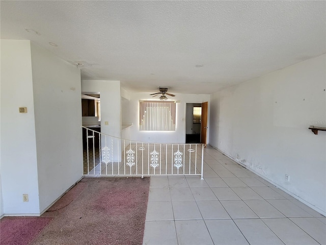 tiled empty room with ceiling fan and a textured ceiling