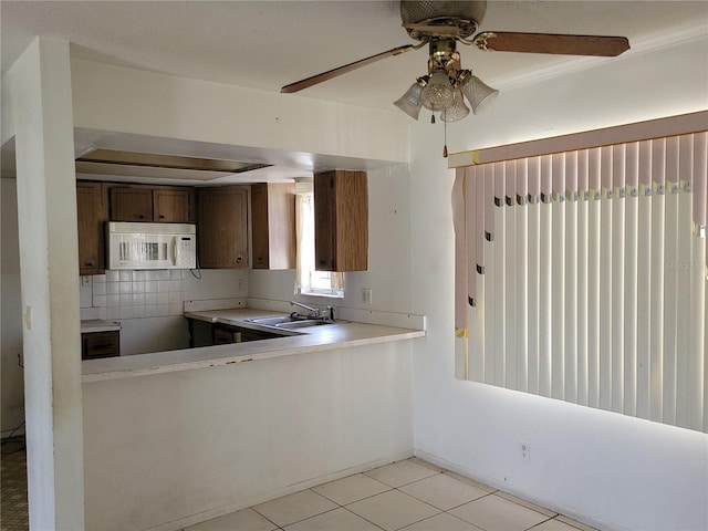 kitchen featuring tasteful backsplash, light tile patterned flooring, sink, and kitchen peninsula