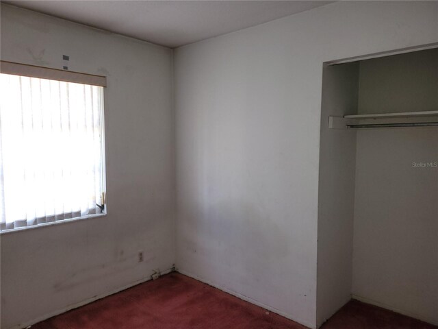 unfurnished bedroom with dark carpet and a closet